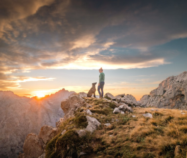 Vrouw loopt met hond door Picos de Europa, het eerste nationale park van Spanje