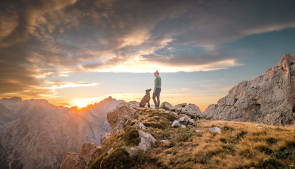 Vrouw loopt met hond door Picos de Europa, het eerste nationale park van Spanje