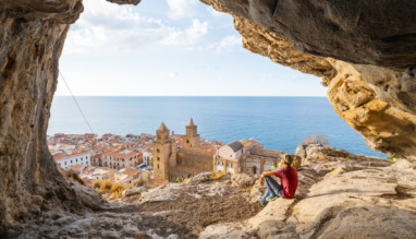Persoon in grot boven Cefalù, Sicilië, kijkt uit over stad en zee