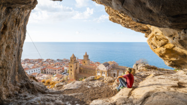 Persoon in grot boven Cefalù, Sicilië, kijkt uit over stad en zee