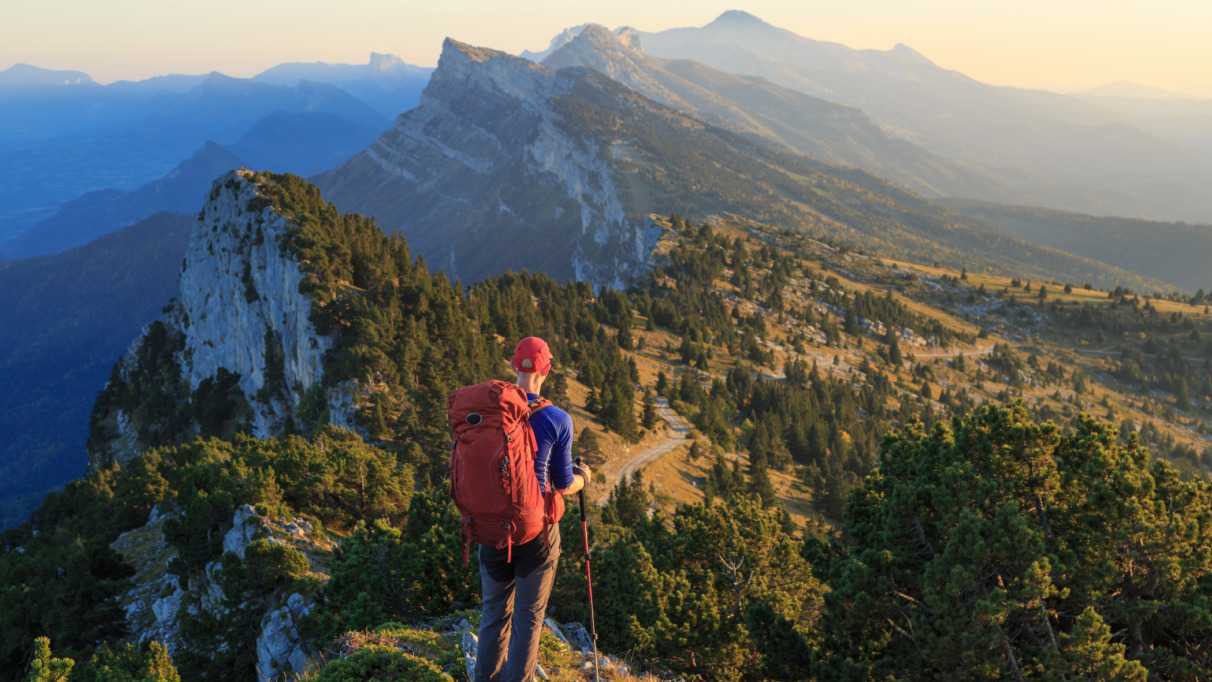 Hiker kijkt uit over de bergen van Vercors, Frankrijk tijdens zonsondergang