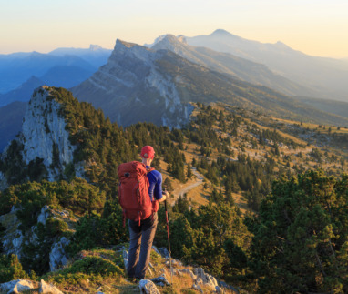 Hiker kijkt uit over de bergen van Vercors, Frankrijk tijdens zonsondergang