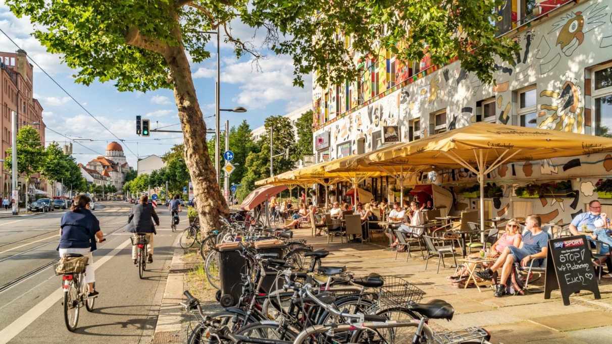 Levendig straatbeeld in de wijk Südvorstadt met kleurrijke gevels, fietspaden en gezellige terrassen.
