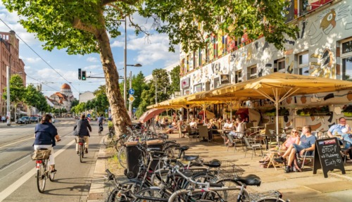 Levendig straatbeeld in de wijk Südvorstadt met kleurrijke gevels, fietspaden en gezellige terrassen.