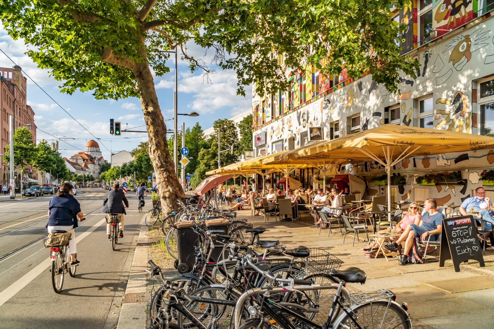 Levendig straatbeeld in de wijk Südvorstadt met kleurrijke gevels, fietspaden en gezellige terrassen.