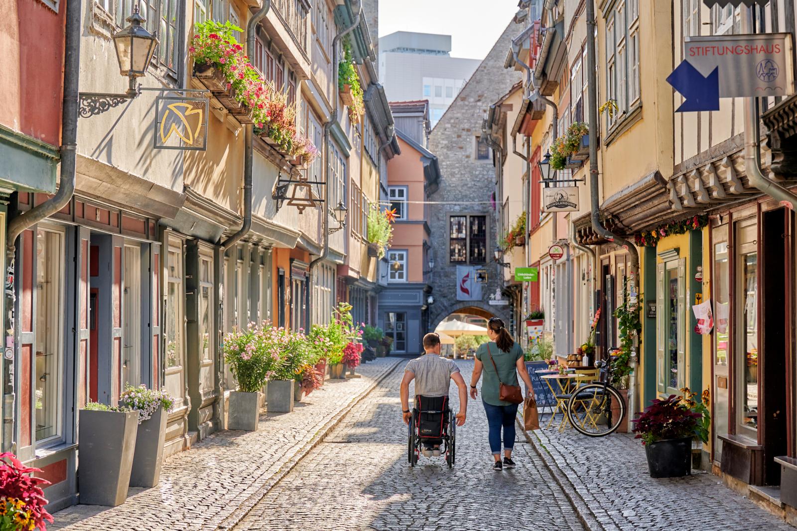 Een koppel wandelt over de kasseien van de historische Krämerbrücke met vakwerkhuizen in Erfurt.