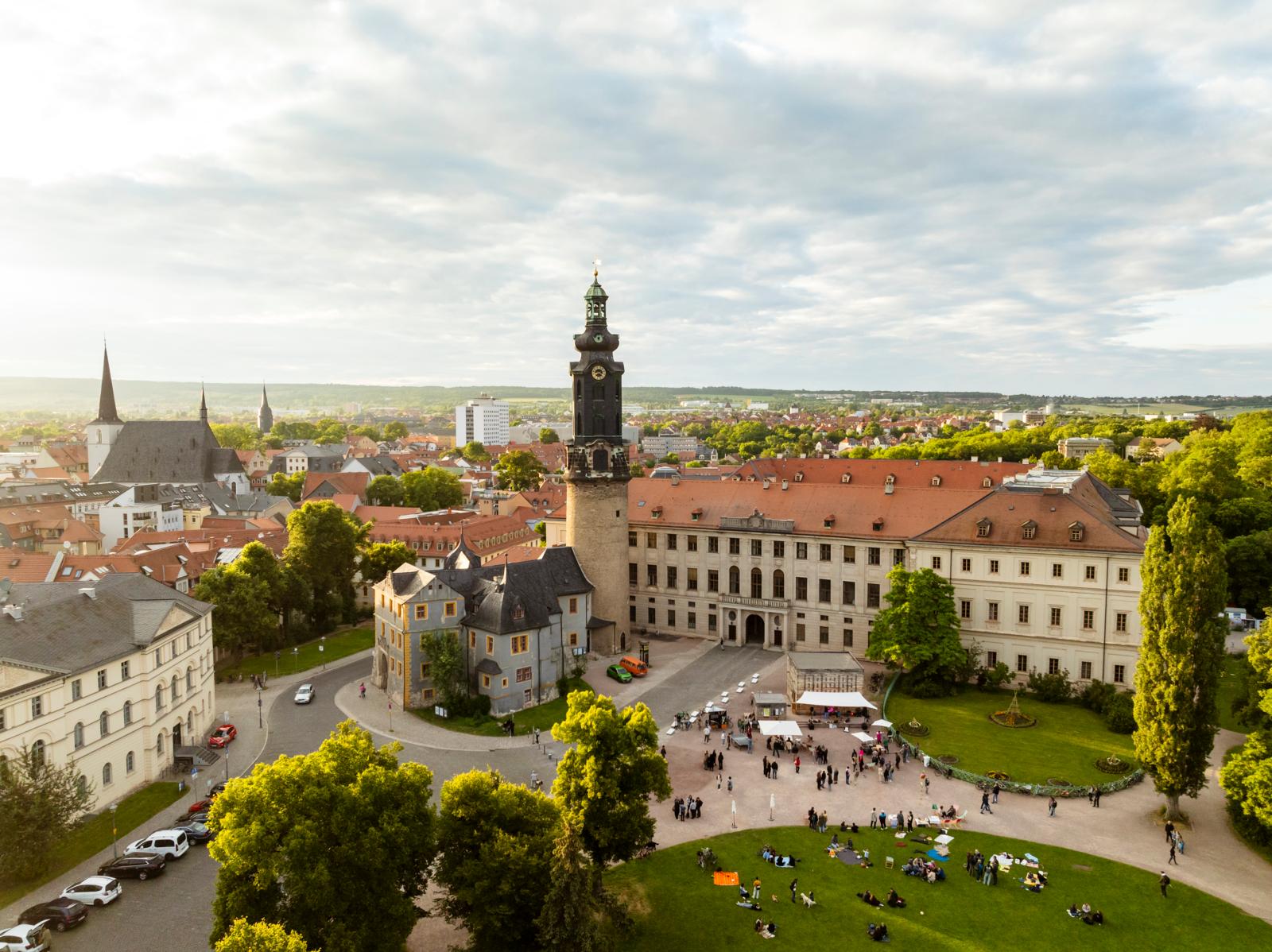 Luchtfoto van het historische Stadtschloss Weimar met de karakteristieke kasteeltoren en mensen in het aangrenzende park.