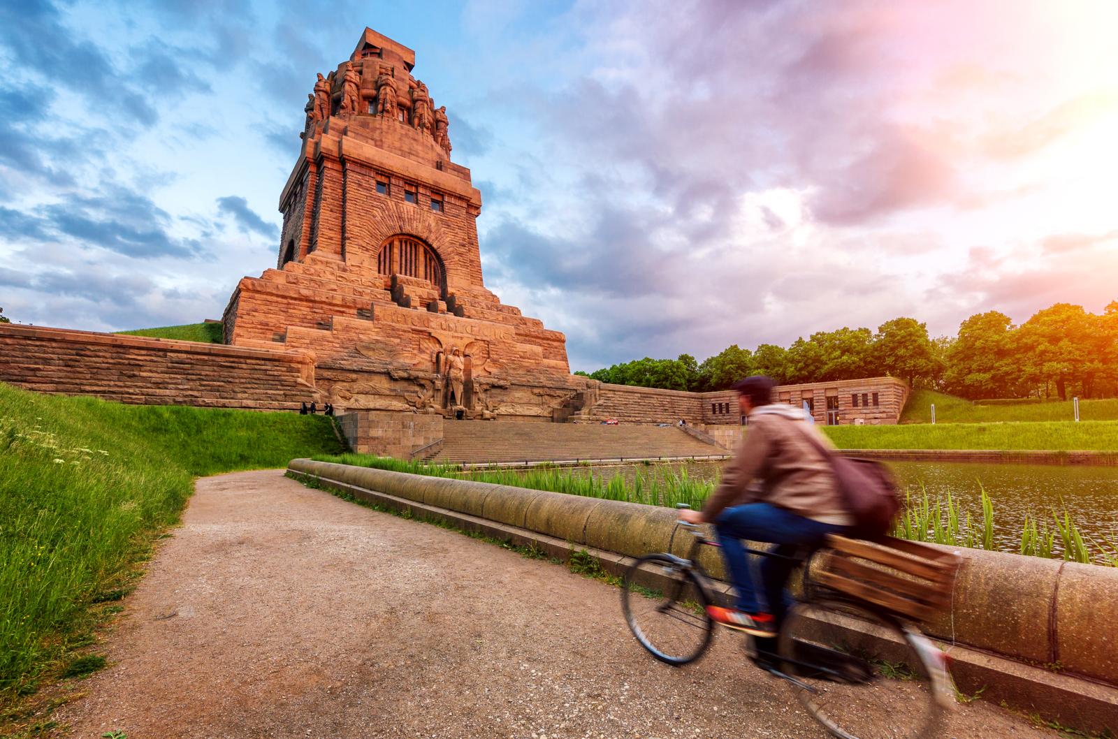 Zijaanzicht van het imposante Völkerschlachtdenkmal in Leipzig met een fietser op de voorgrond.