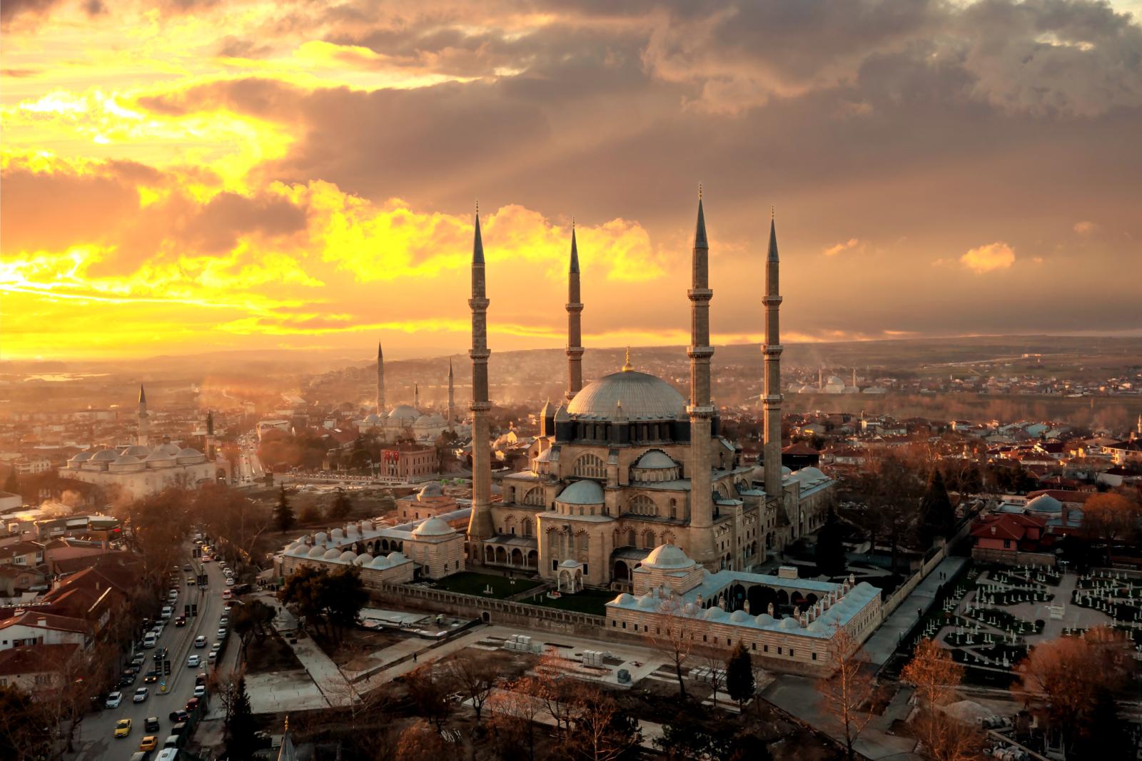 Een panoramisch bovenaanzicht van de Selimiye-moskee met haar vier slanke minaretten en grote koepel, badend in het warme licht van een dramatische zonsondergang boven Edirne.