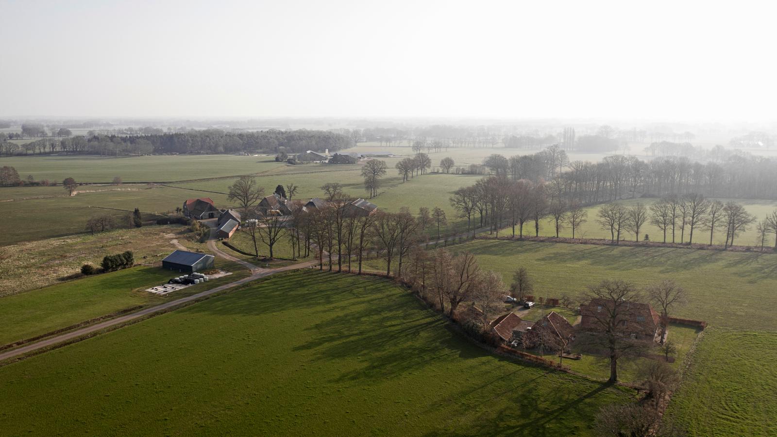 Luchtfoto van het landelijke Achterhoekse coulisselandschap met groene velden, boerderijen, bomen en fietsers.