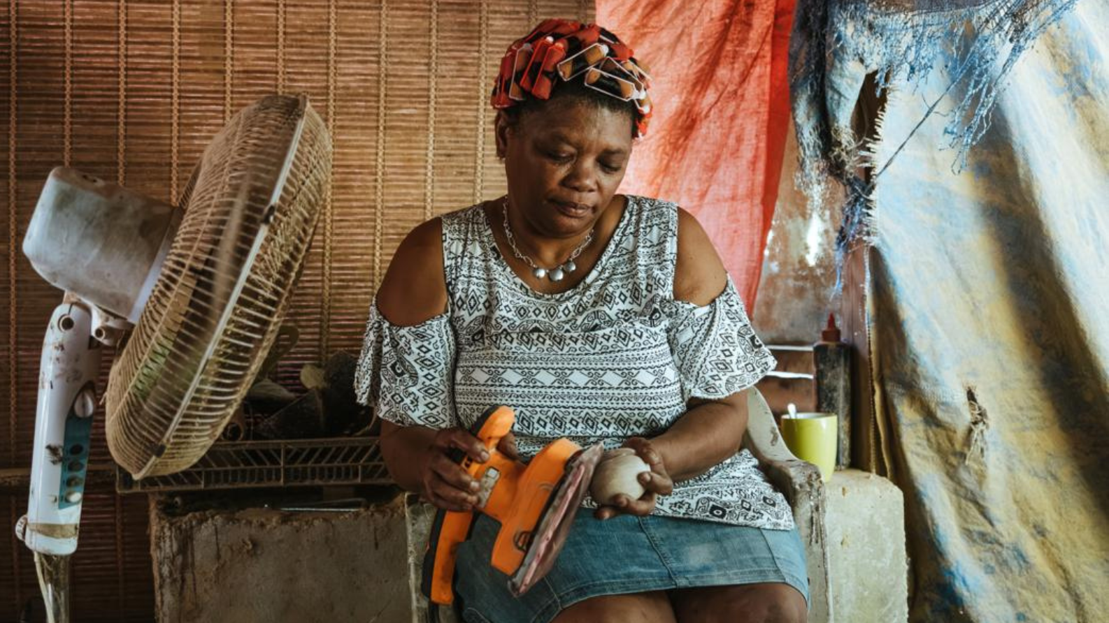 Vrouw op de Seychellen schuurt met de hand een kokosnoot in een kleine ambachtelijke werkplaats