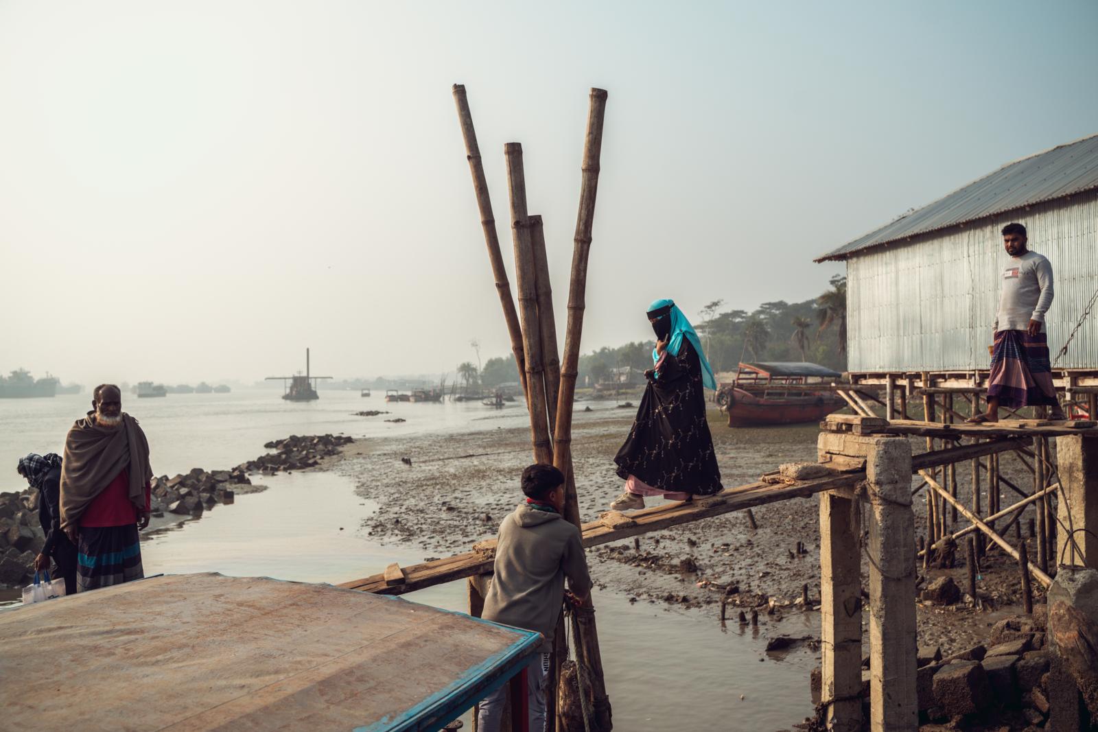 bewoners steken houten loopplank over aan rivier in de Sundarbans van Bangladesh