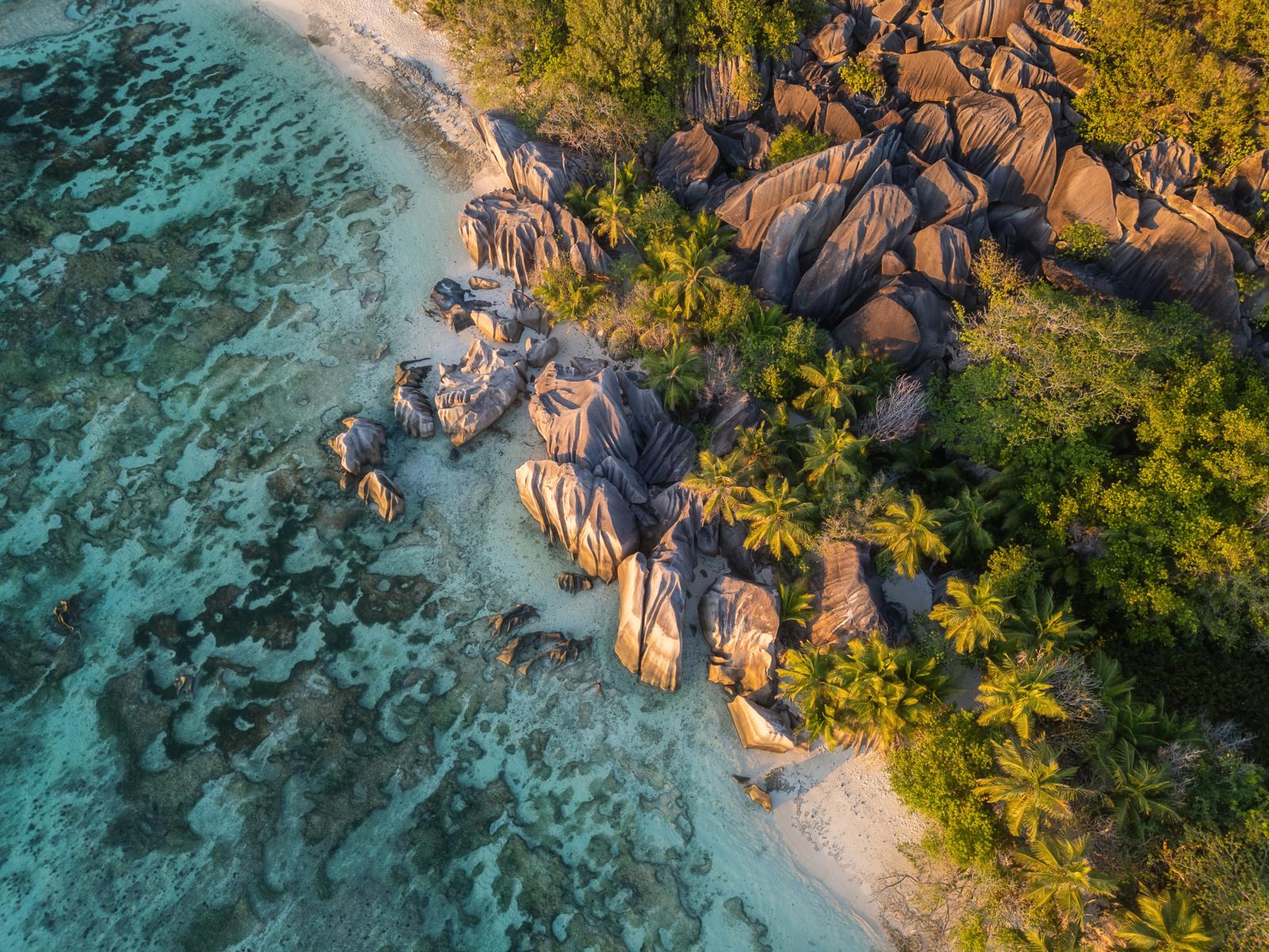Luchtfoto van turquoise zee, granietrotsen en palmenstrand bij Anse Source d’Argent op de Seychellen