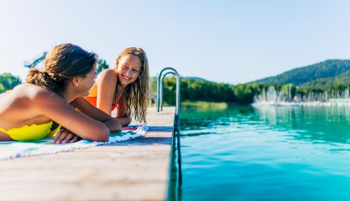 Twee meisjes relaxen op een steiger aan de Wörthersee in Oostenrijk