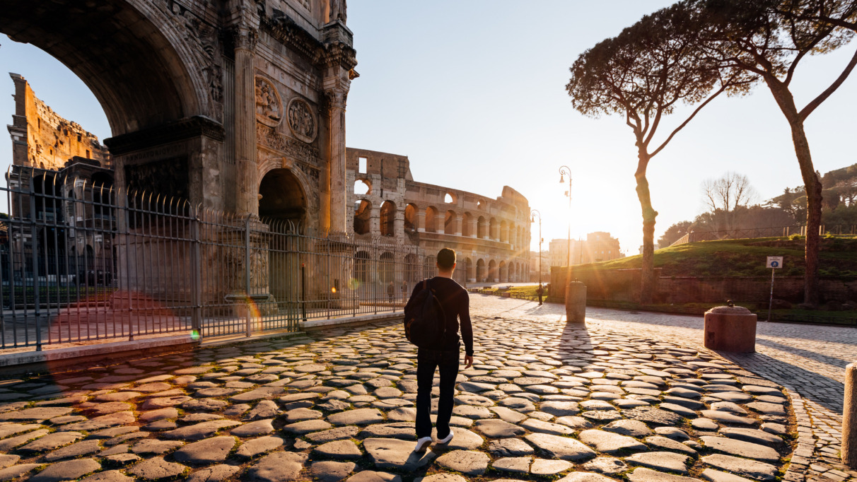 Achterkant van een man die bij zonsopgang de oude bezienswaardigheden van Rome verkent, Italië