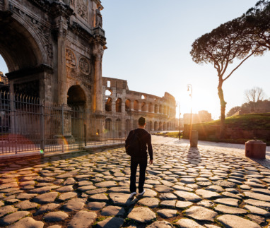 Achterkant van een man die bij zonsopgang de oude bezienswaardigheden van Rome verkent, Italië