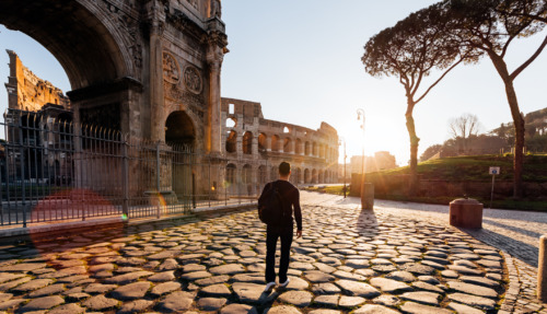Achterkant van een man die bij zonsopgang de oude bezienswaardigheden van Rome verkent, Italië