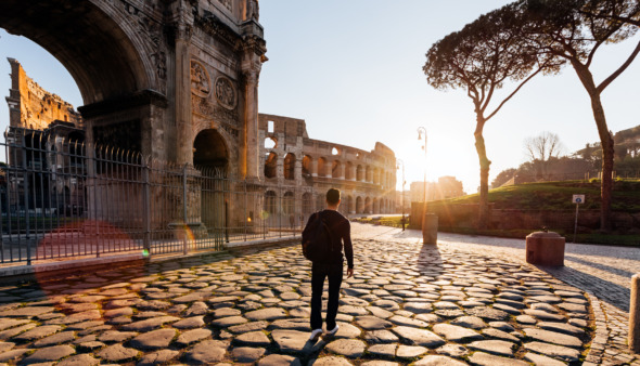 Achterkant van een man die bij zonsopgang de oude bezienswaardigheden van Rome verkent, Italië