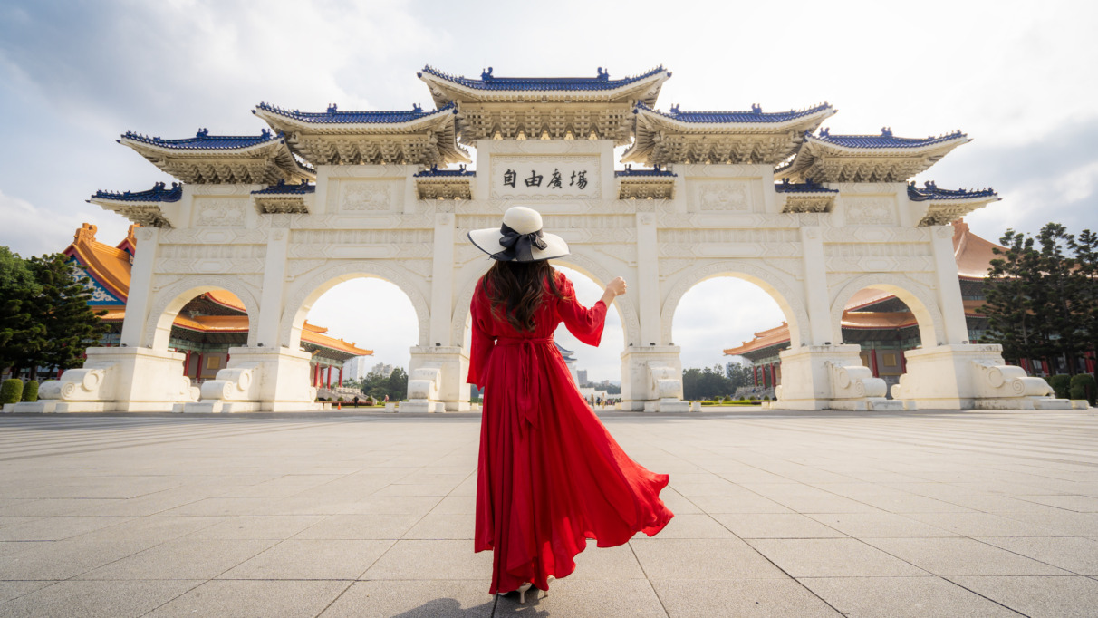 Een vrouwelijke toeriste in een rode jurk bij de poort van het Chiang Kai-shek-herdenkingsmonument in de ochtend, Taipei, Taiwan.