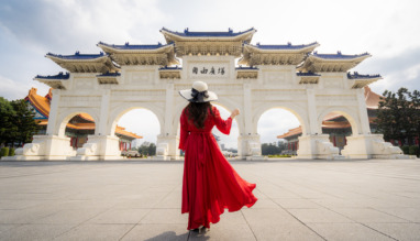 Een vrouwelijke toeriste in een rode jurk bij de poort van het Chiang Kai-shek-herdenkingsmonument in de ochtend, Taipei, Taiwan.