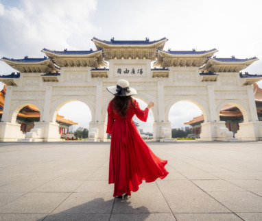 Een vrouwelijke toeriste in een rode jurk bij de poort van het Chiang Kai-shek-herdenkingsmonument in de ochtend, Taipei, Taiwan.