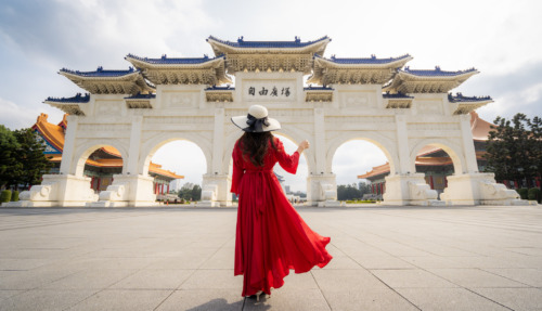 Een vrouwelijke toeriste in een rode jurk bij de poort van het Chiang Kai-shek-herdenkingsmonument in de ochtend, Taipei, Taiwan.