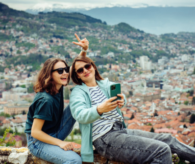 Twee vrolijke meiden maken selfies met Sarajevo, Bosnie op de achtergrond