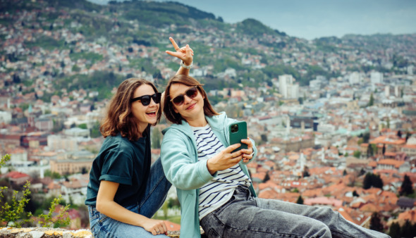 Twee vrolijke meiden maken selfies met Sarajevo, Bosnie op de achtergrond