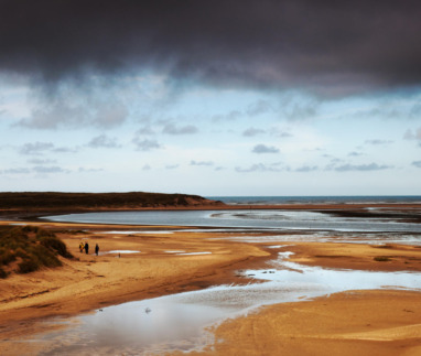 Panoramisch uitzicht over de kreken en duinen van natuurgebied De Slufter op Texel onder een dreigende lucht.