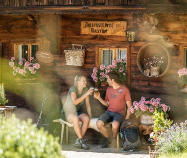 Stelletje rust bij een berghut in het Alpbachtal in Oostenrijk en proost met een biertje