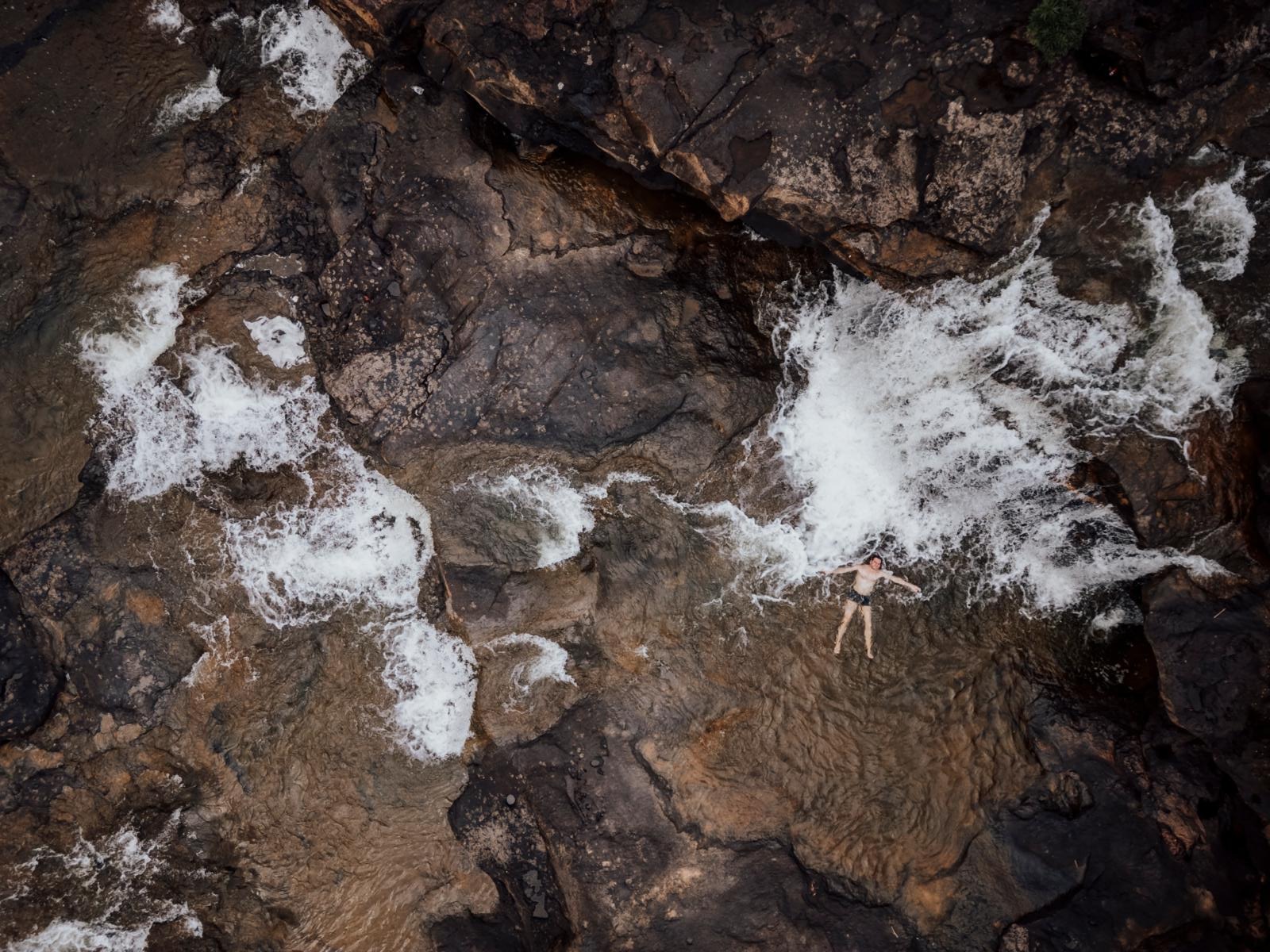 Reiziger ontspant in een natuurlijke poel onder een waterval in de Cardamom Mountains van Cambodja