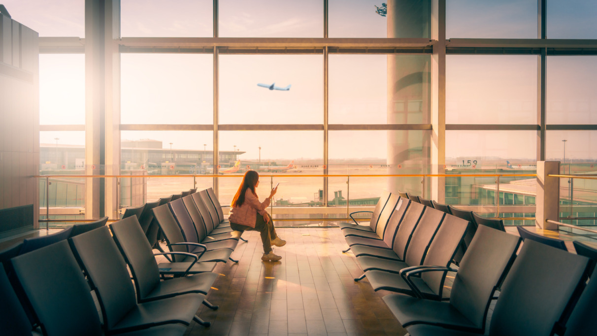 Vrouw wacht bij de gate van de luchthaven tijdens zonsondergang