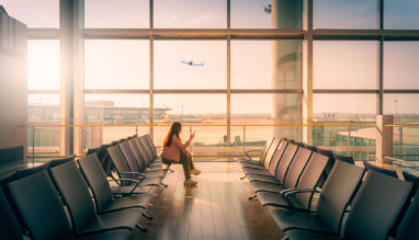 Vrouw wacht bij de gate van de luchthaven tijdens zonsondergang