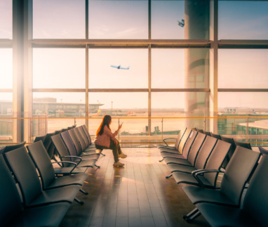 Vrouw wacht bij de gate van de luchthaven tijdens zonsondergang
