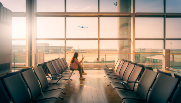 Vrouw wacht bij de gate van de luchthaven tijdens zonsondergang
