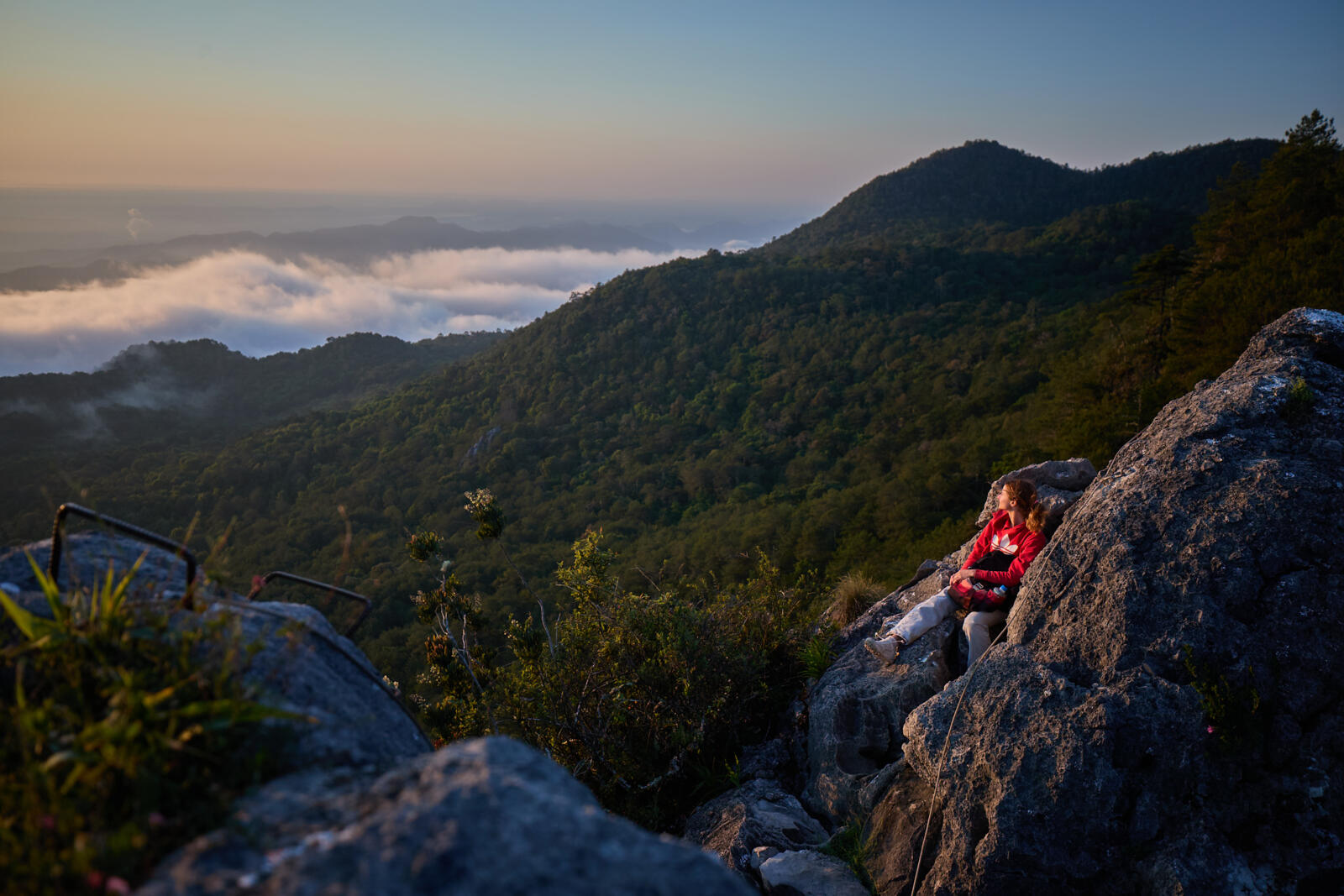Een wandelaar geniet tijdens zonsopgang zittend op een rots van het weidse uitzicht over het berglandschap van de Sierra Gorda bij het dorpje Trinidad, Mexico.