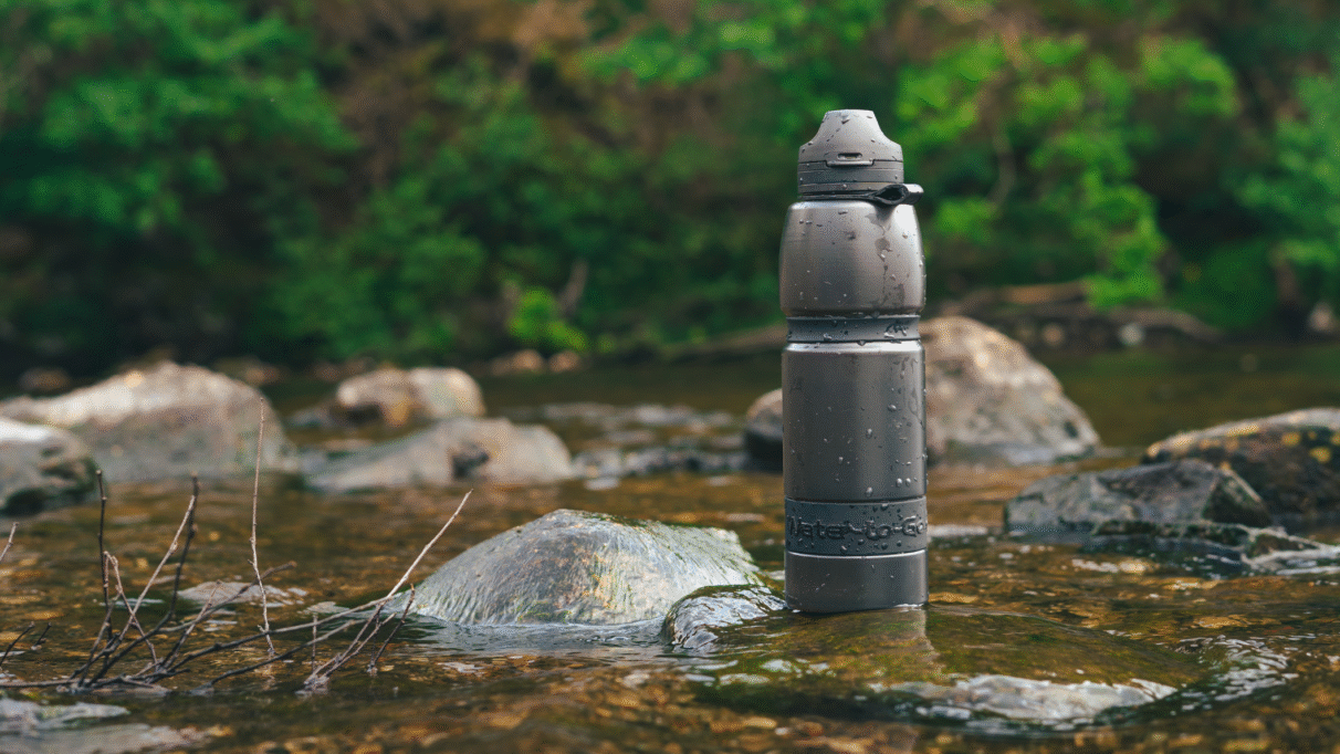 Zwarte Water-to-Go filterfles op een rots in een stromende rivier
