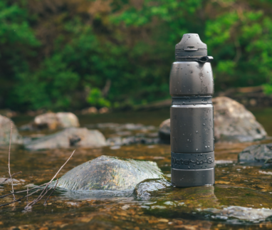 Zwarte Water-to-Go filterfles op een rots in een stromende rivier