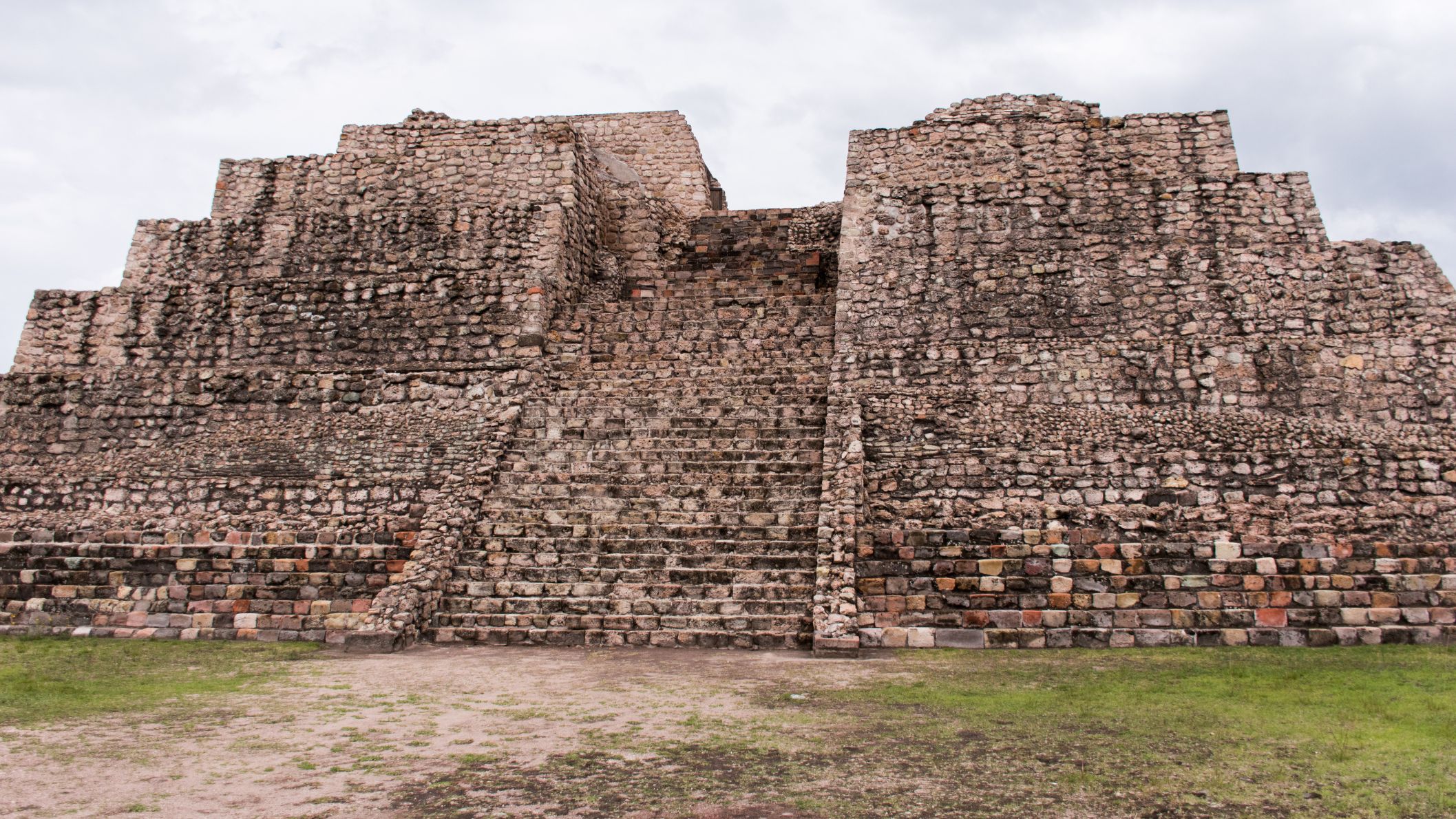 De imposante stenen piramide en tempelstructuur van de archeologische vindplaats Cañada de la Virgen in Mexico onder een bewolkte lucht.