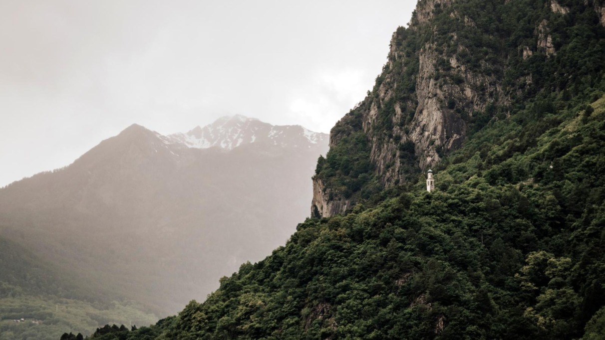 Kleine Mariakapel op een beboste berghelling in Valchiavenna, omringd door steile rotswanden en Alpentoppen