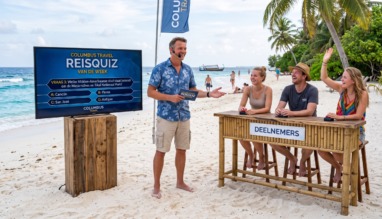 Quizmaster speelt met deelnemers de Columbus travel reisquiz van de week op het strand