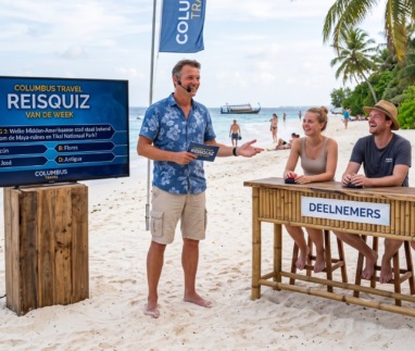 Quizmaster speelt met deelnemers de Columbus travel reisquiz van de week op het strand