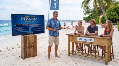 Quizmaster speelt met deelnemers de Columbus travel reisquiz van de week op het strand