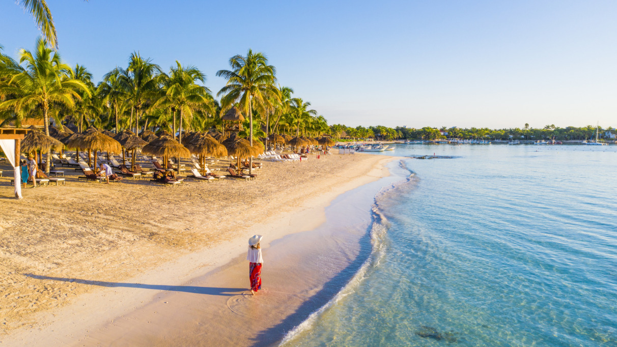 Vrouw die over een Caribisch strand in Akumal, Mexico, loopt