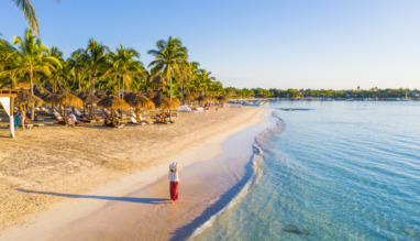 Vrouw die over een Caribisch strand in Akumal, Mexico, loopt