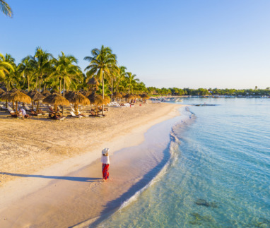 Vrouw die over een Caribisch strand in Akumal, Mexico, loopt