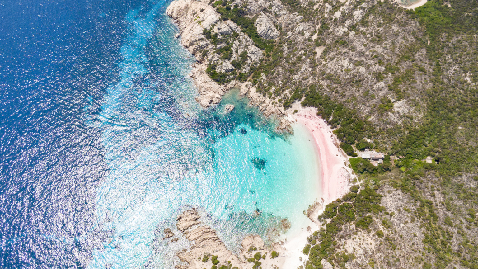 Wie zoekt naar roze stranden komt al snel uit bij Spiaggia Rosa op het Italiaanse eiland Budelli bij Sardinië. Dit strand gold ooit als een van de felste roze stranden ter wereld, maar is dat helaas niet meer. Nadat het strand decennialang werd geteisterd door massatoerisme en bezoekers kilo's souvenirzand meenamen, verdween de iconische kleur. Tegenwoordig is het strand vrijwel wit. Het eiland is inmiddels streng beschermd: betreding van het strand is verboden en je mag de baai alleen nog vanaf een boot op afstand bewonderen.