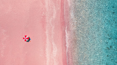 Luchtfoto van parasol op een roze strand
