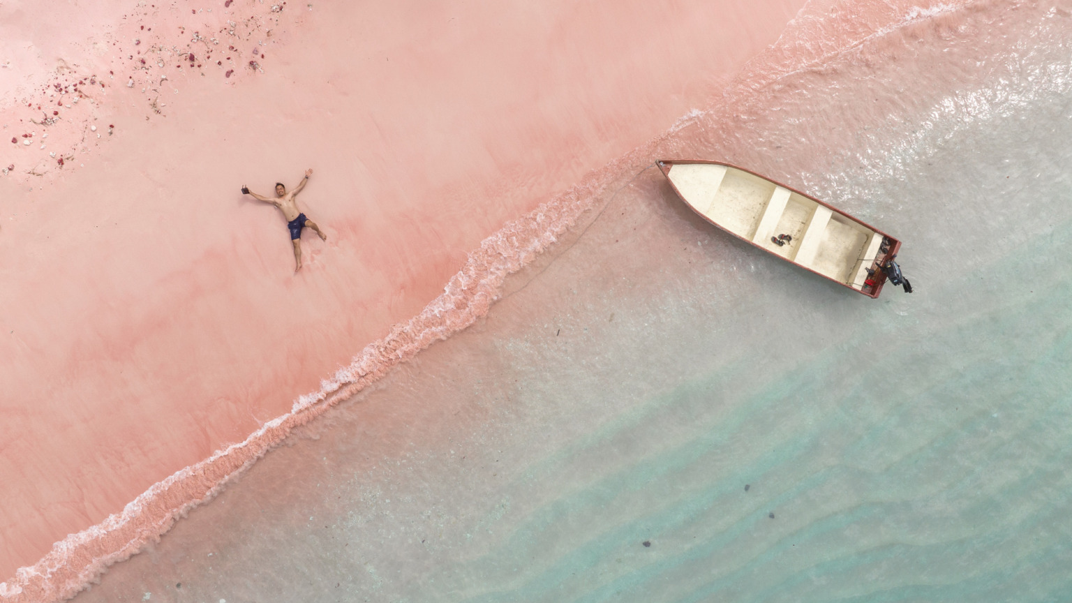 Luchtfoto van een man die op Pink Beach op het eiland Komodo in Indonesië ligt