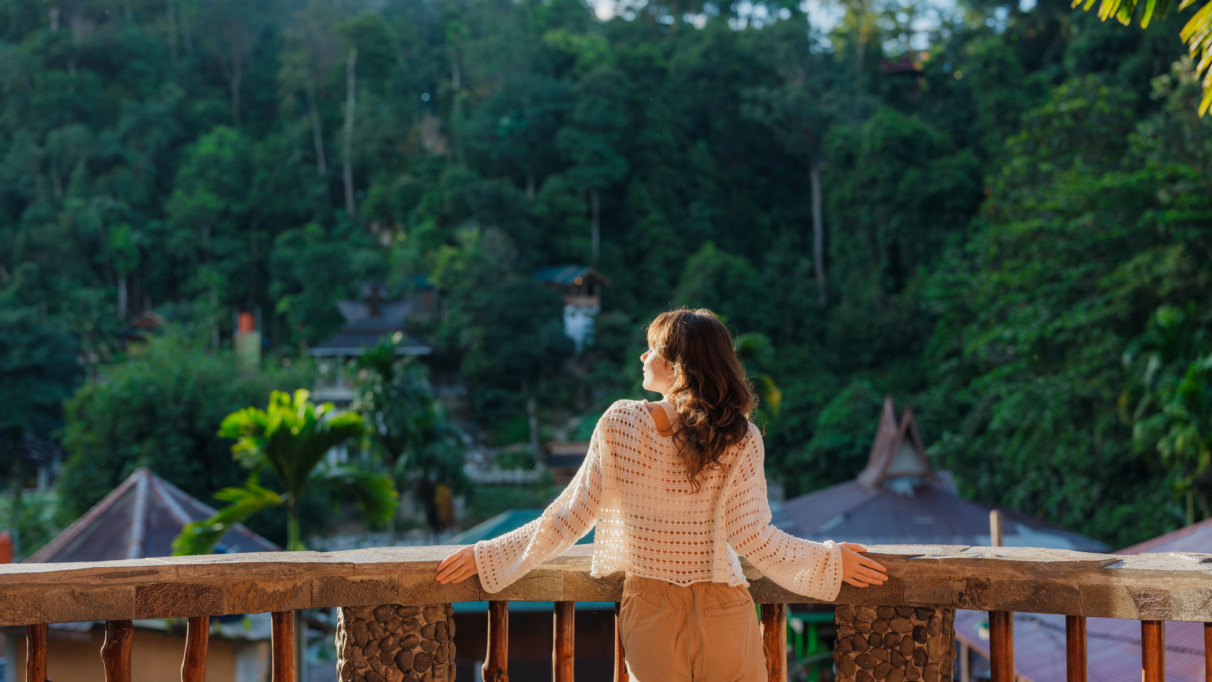 Vrouw op het balkon van een resort tijdens haar reis naar de jungle in Bukit Lawang, Sumatra, Indonesië